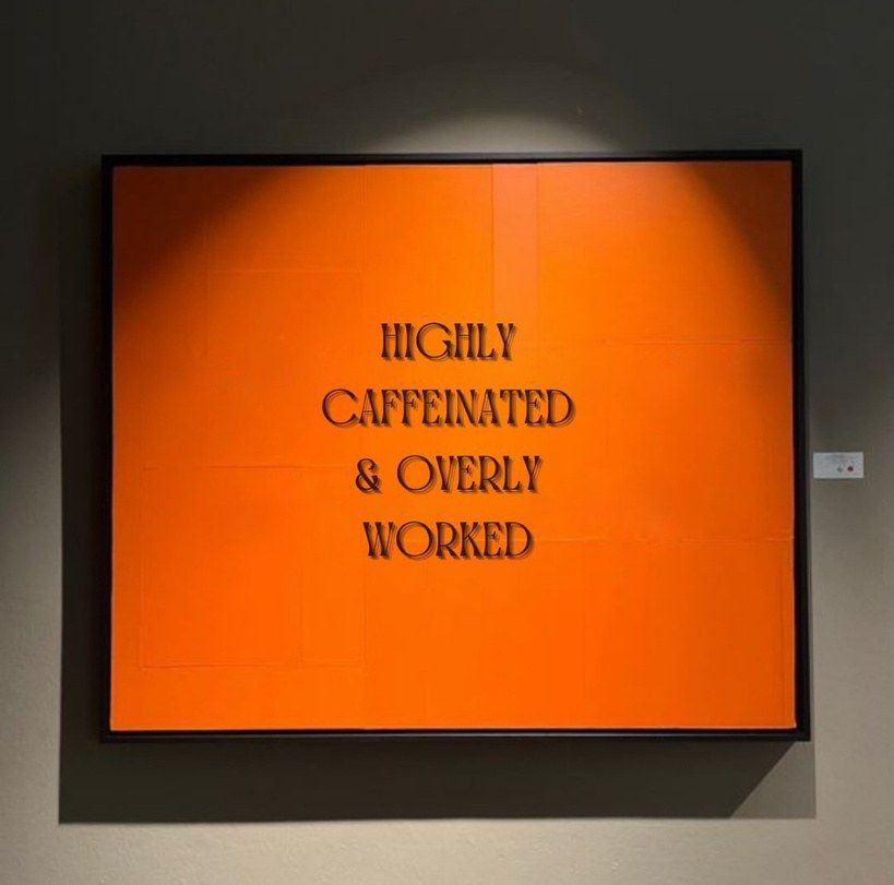 Orange print in the studio reading Highly caffeinated and overly worked